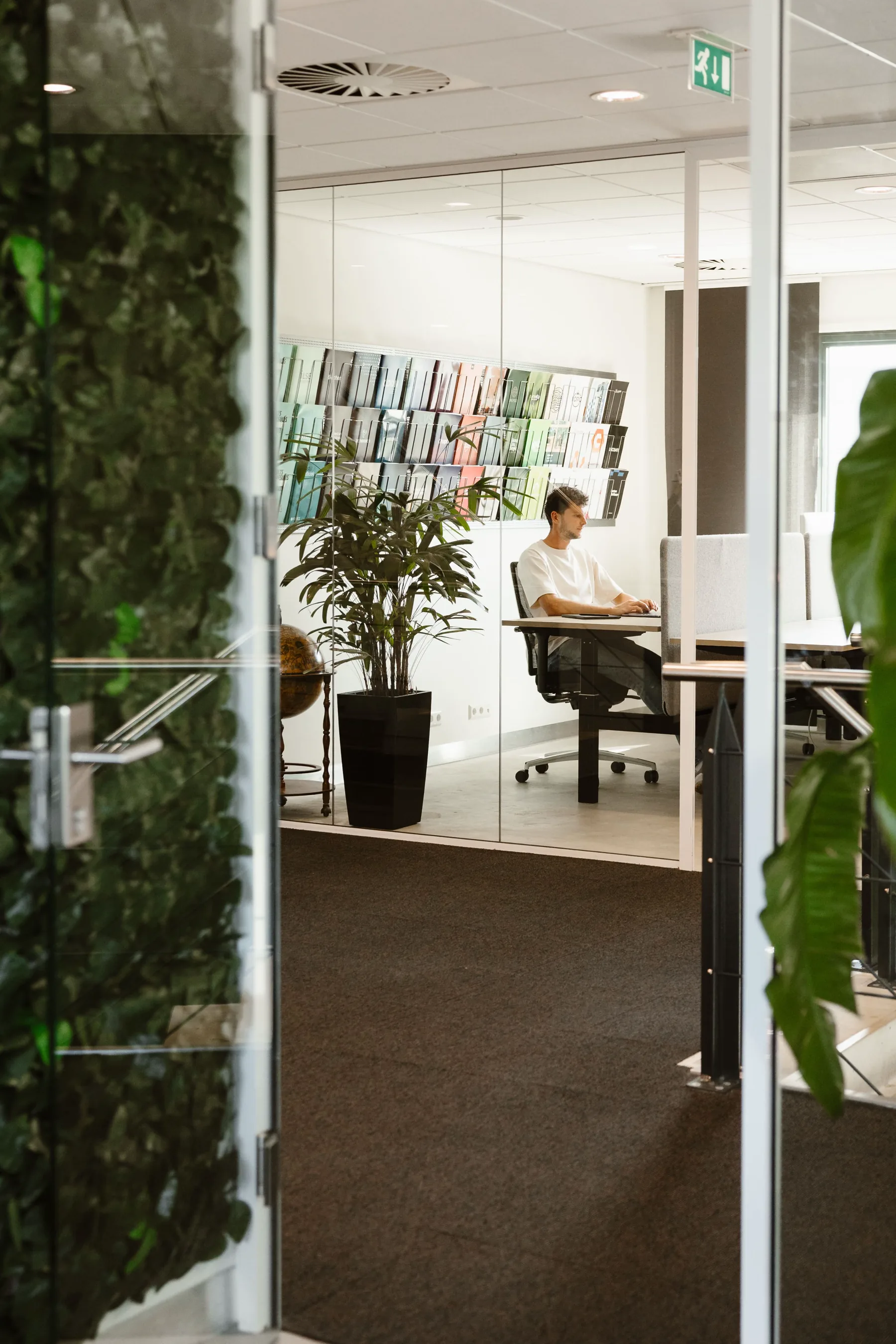 Werkplek in het kantoor van Huray met glazen wanden en veel groen.